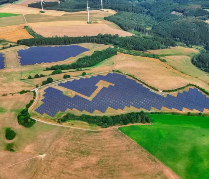 Aerial view of the Heckhuscheid solar park in a hilly landscape with wind turbines